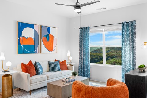 A living room with a white couch, orange chair, and two abstract paintings on the wall.