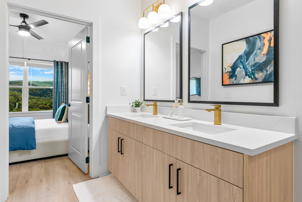 A bathroom with a large mirror, a sink, and a bedroom with a window.