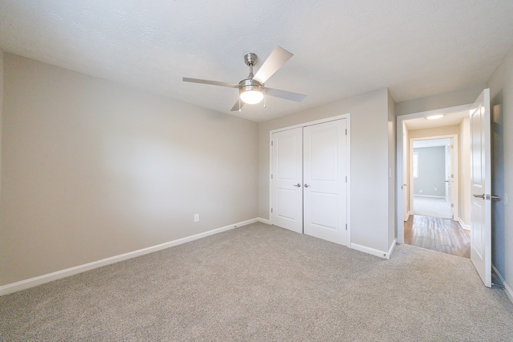 A room with a ceiling fan and carpeted floor.