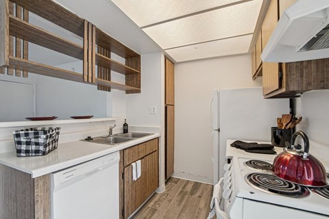 A small kitchen with a white stove top oven and a white dishwasher.