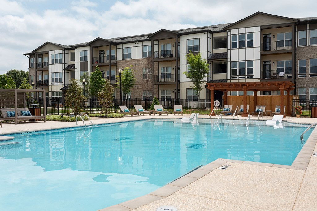an apartment swimming pool with chairs in front of an apartment building at The Cannon, Tennessee