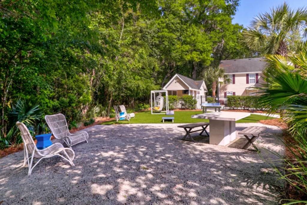 a yard with a table and chairs and a house in the background at Enclave at West Ashley Apartments, Charleston,32304