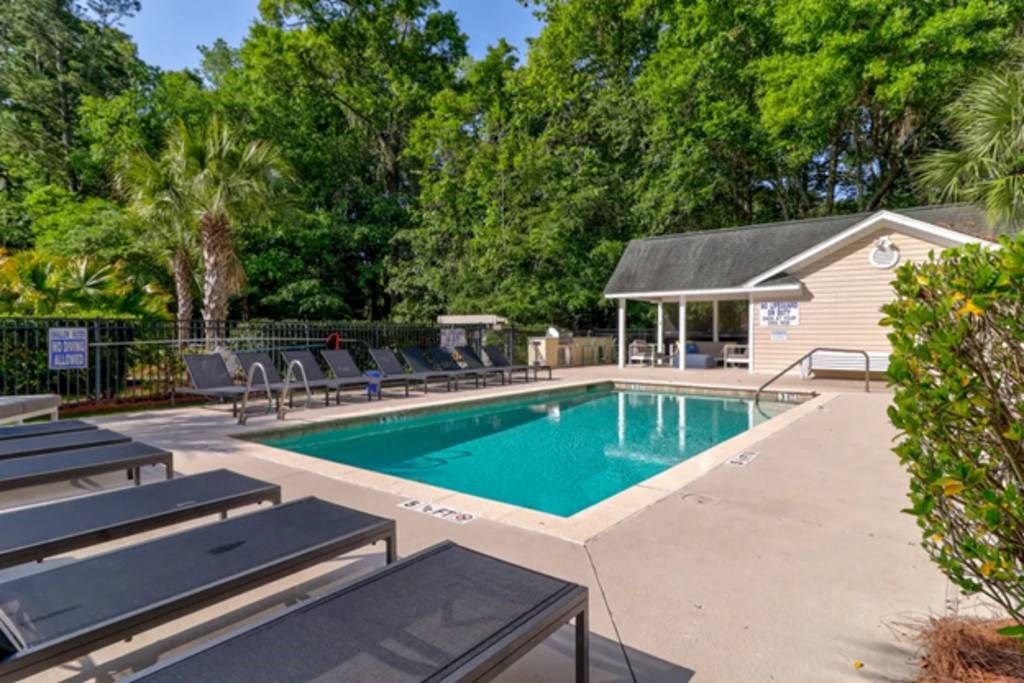 a swimming pool with chaise lounge chairs and trees in the background at Enclave at West Ashley Apartments, Charleston,SC