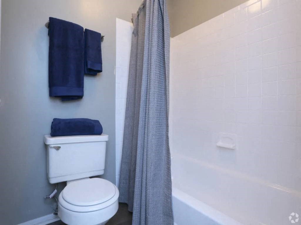 a bathroom with a toilet and a shower and blue towels