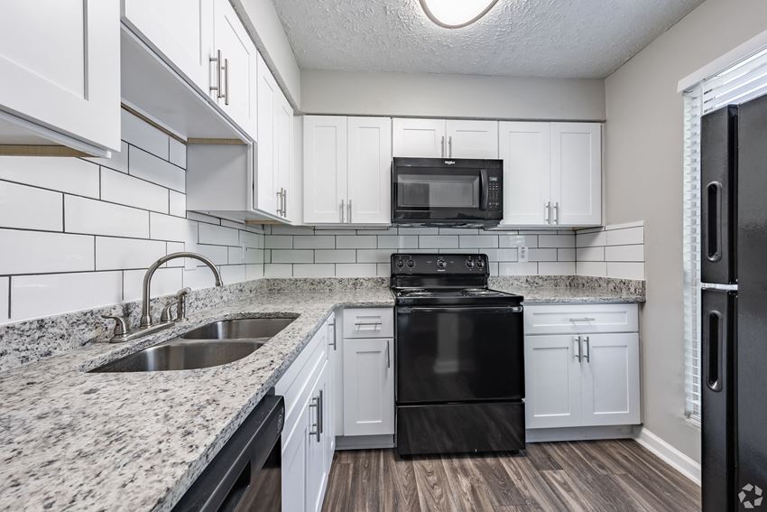 a kitchen with white cabinets and black appliances - Photo Gallery