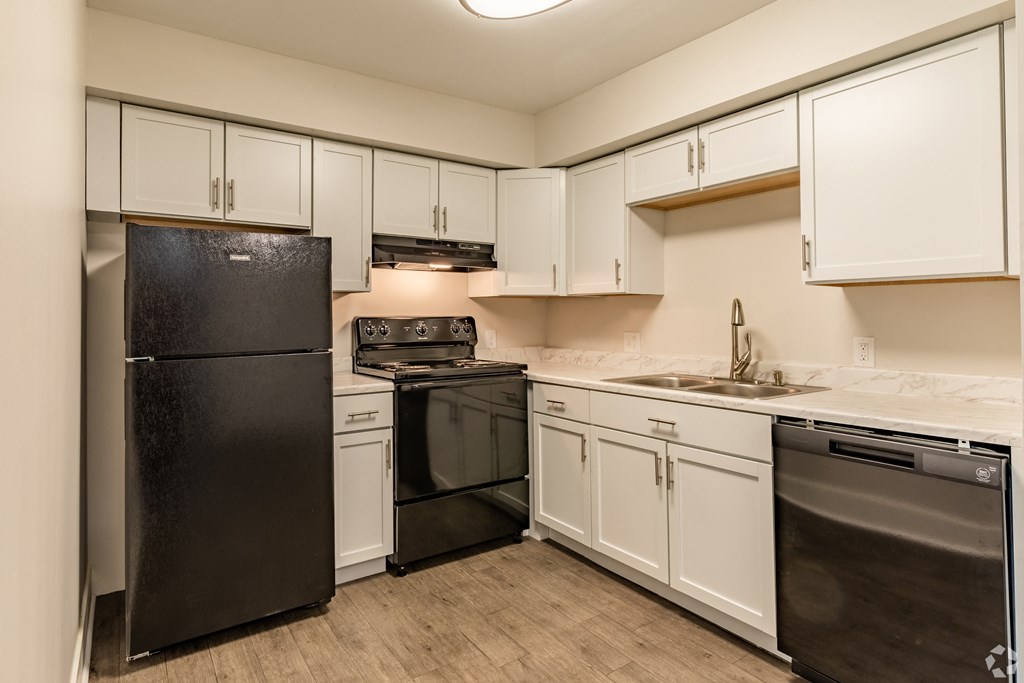 a kitchen with white cabinets and black appliances