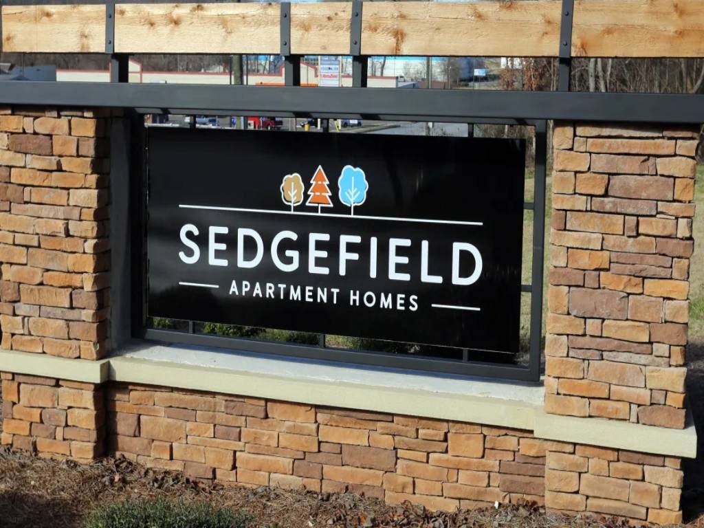 a sign for sedgefield apartment homes in front of a brick building