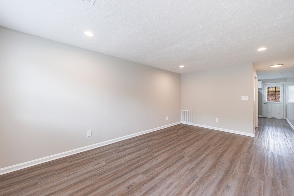 A room with wooden flooring and a doorway leading to another room.