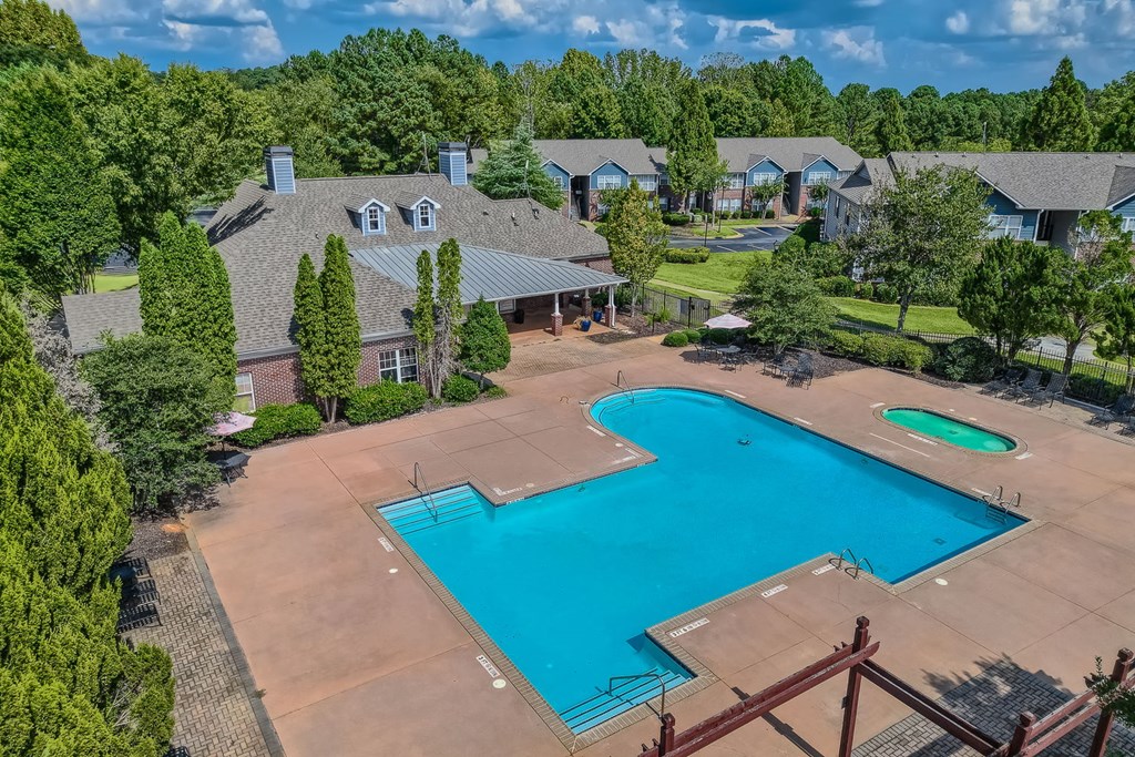 an aerial view of a swimming pool with a house in the background