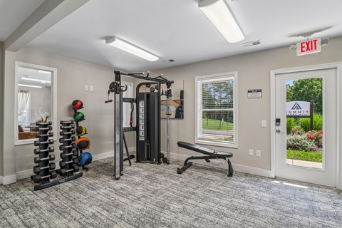 A gym room with a bench, weights, and a window.