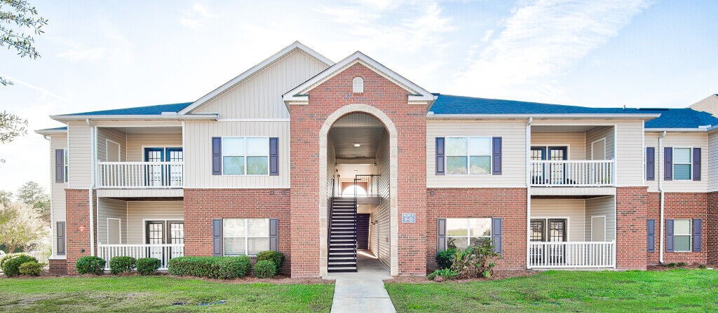 A two-story brick apartment building with a balcony on the second floor.