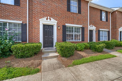 A red brick house with a black front door and windows.