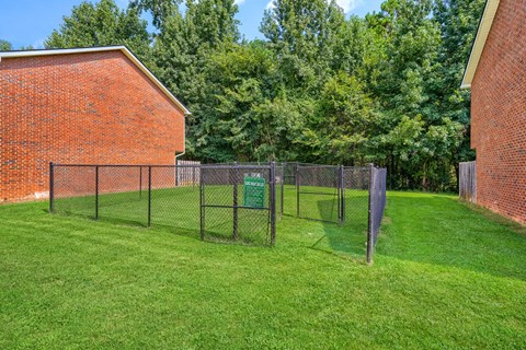 A green sign is on a fence in a grassy yard.