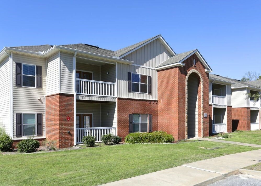 A brick building with a white roof and a balcony.