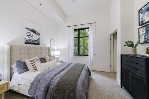 A bedroom with a large bed and a window with a view of trees.