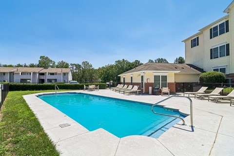 A swimming pool surrounded by lounge chairs and buildings.