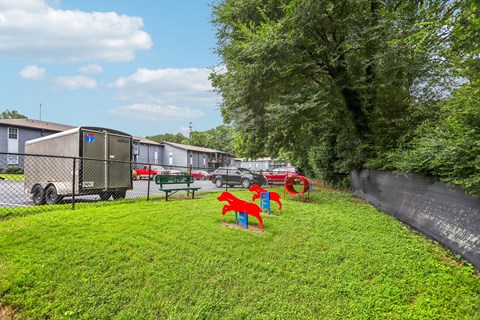 A playground with red and blue slides is in the foreground of a grassy area.
