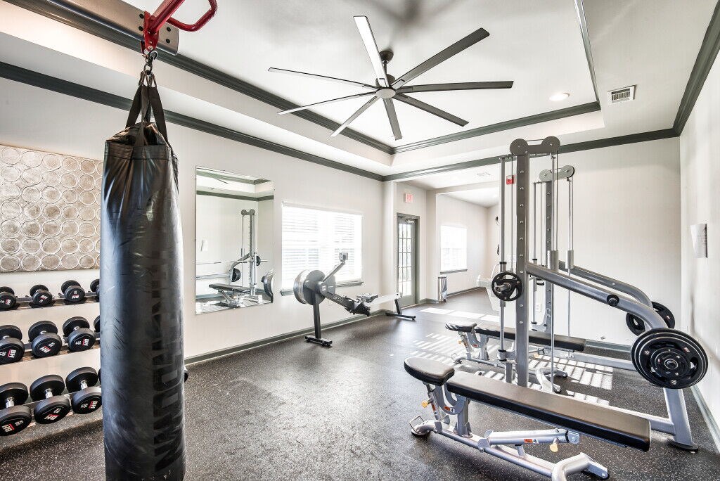 A gym with a punching bag, weights, and a ceiling fan.