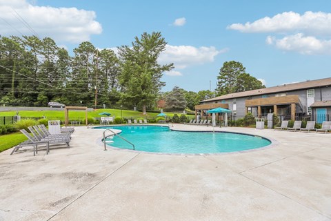 A swimming pool surrounded by concrete and lounge chairs.