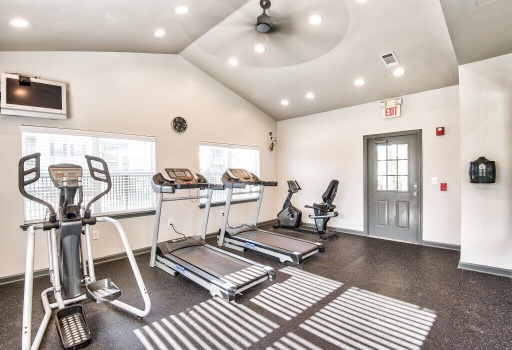 A gym with treadmills, elliptical machines, and a fan.