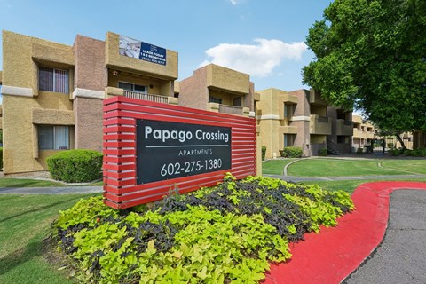 A sign for Papago Crossing Apartments is in front of a building.