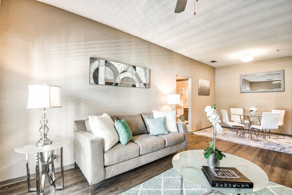 A living room with a grey couch, a white coffee table, and a white ceiling fan.