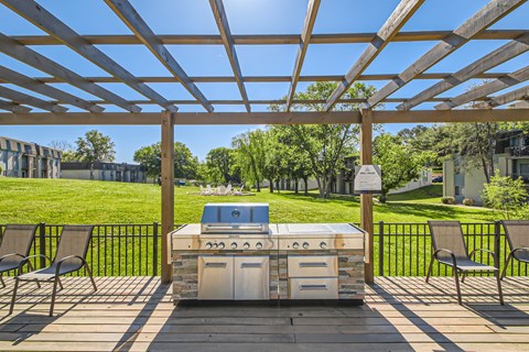 a patio with a grill and chairs under a roof