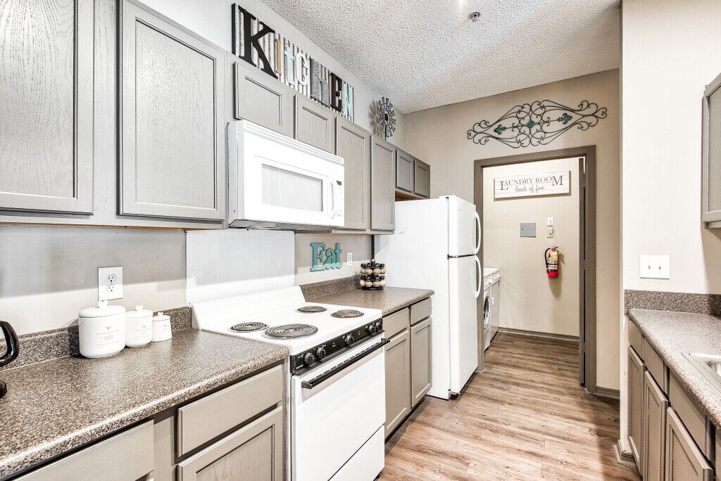 A kitchen with a white stove top oven and white refrigerator.