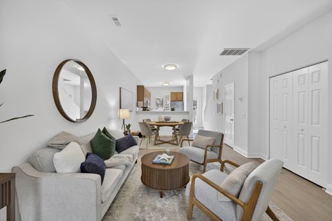 A living room with a grey couch and a round mirror on the wall.