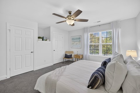 Large bedroom at Townes at Prior with a ceiling fan and large window with coverings.