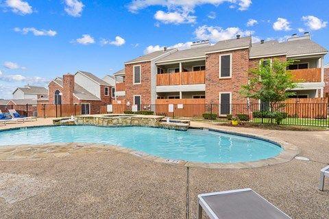 A swimming pool in front of a brick building.
