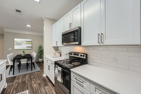 A modern kitchen with white cabinets and a black stove top.
