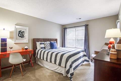 a bedroom with a bed and a desk and a window
