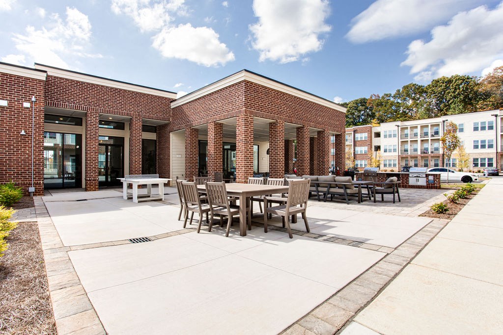 a patio with tables and chairs in front of a brick building at The Indigo Apartments, Georgia