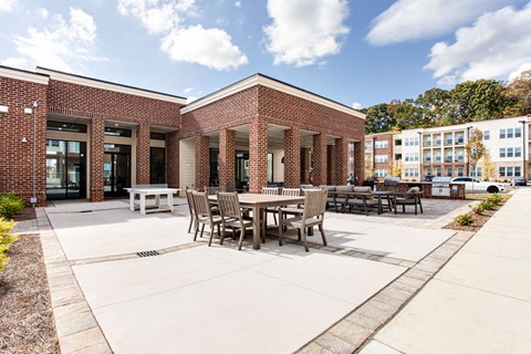a patio with tables and chairs in front of a brick building at The Indigo Apartments, Georgia