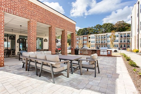 a patio with a table and chairs in front of a brick building at The Indigo Apartments, Canton, GA