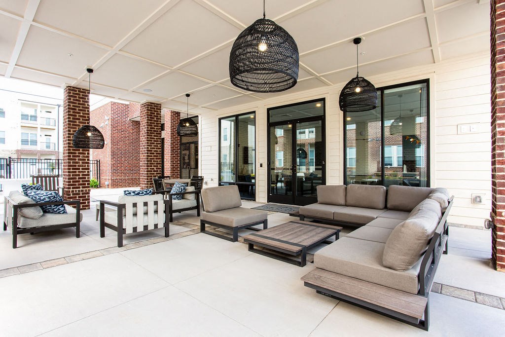 a patio with couches chairs and tables and windows at The Indigo Apartments, Canton