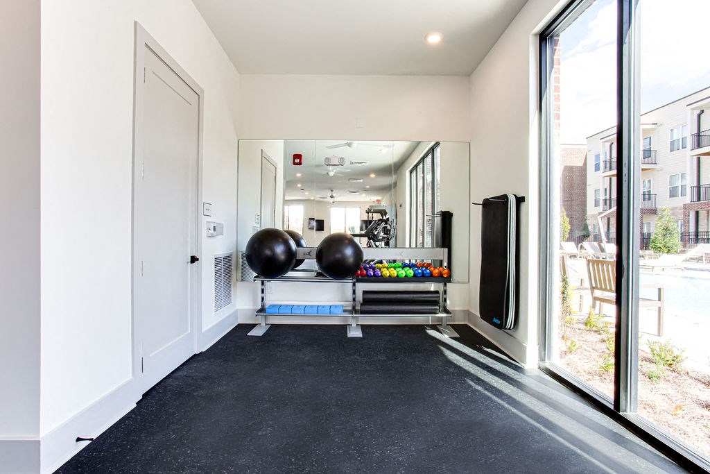 the gym with large windows and black carpeted flooring at The Indigo Apartments, Canton, GA