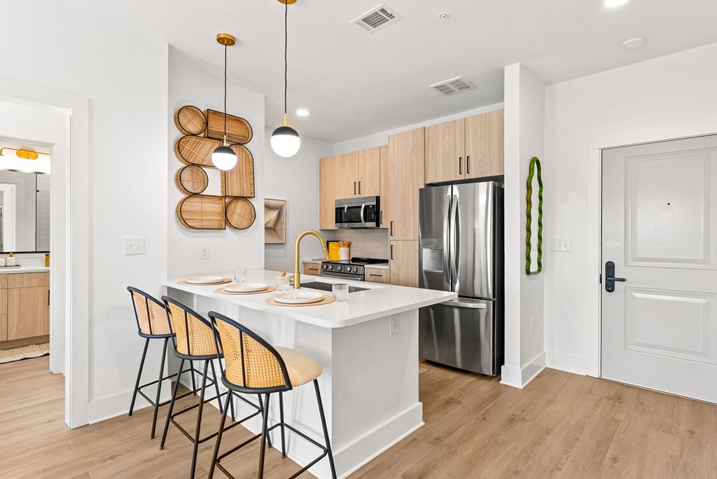 A kitchen with a white island and chairs.