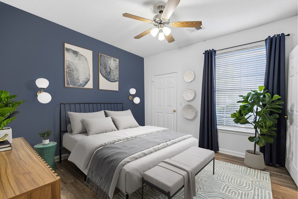 A bedroom with a bed, a ceiling fan, and two wall art pieces.