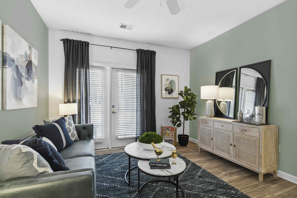 A living room with a grey couch, a round table, and a large mirror.