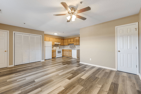 an empty living room and kitchen with a ceiling fan