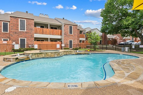 A pool surrounded by a black fence with a sign that says no diving.