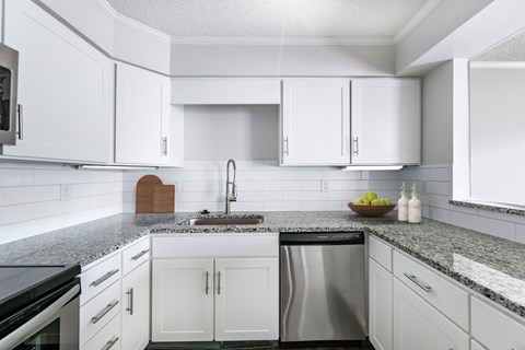 A kitchen with white cabinets and a granite countertop.