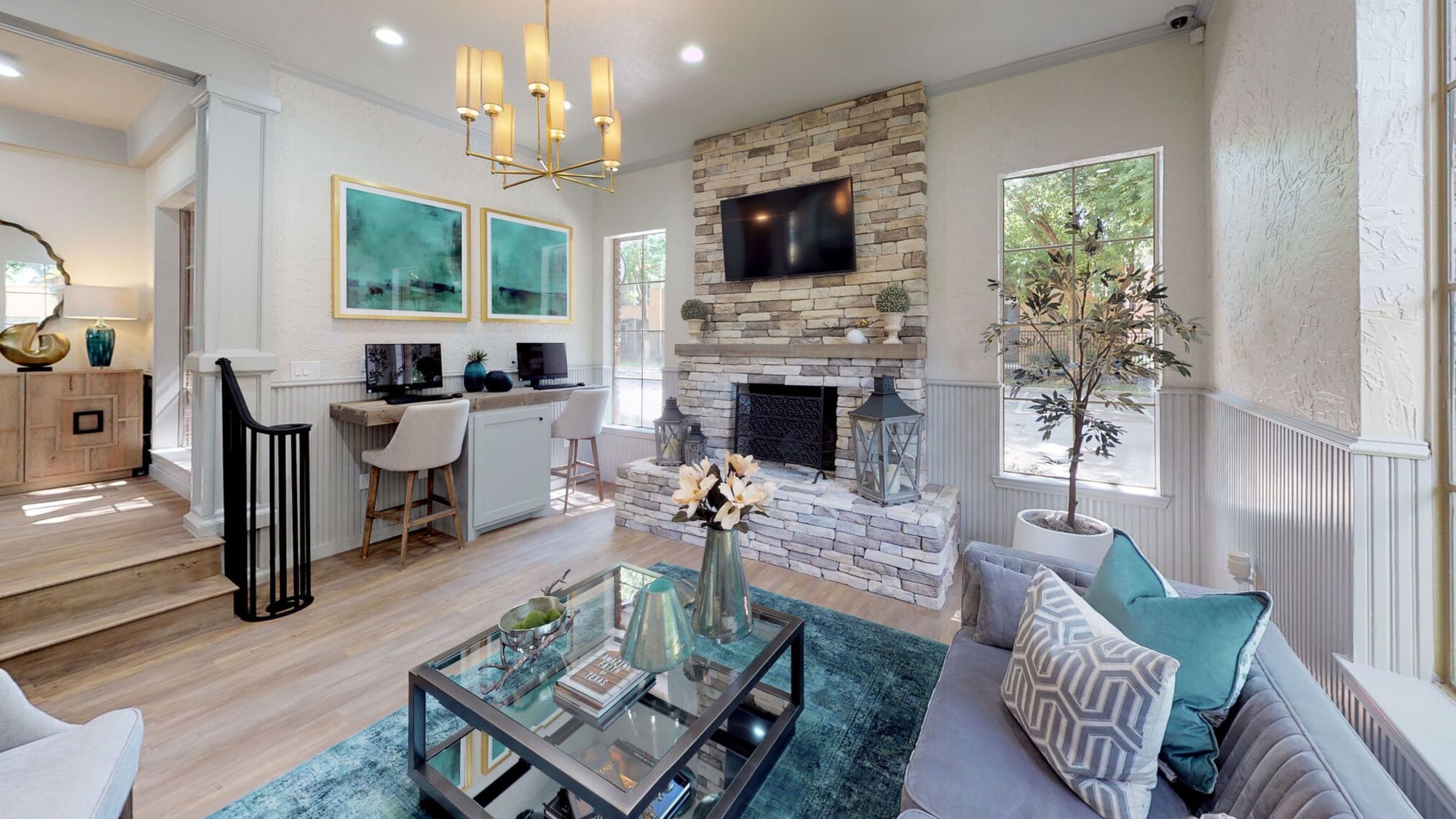 A living room with a stone fireplace and a glass coffee table.