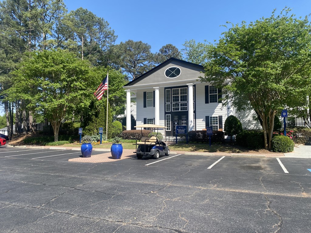 a white building with a lawnmower parked in front of it at Vinings RiverVue Apartments, Atlanta