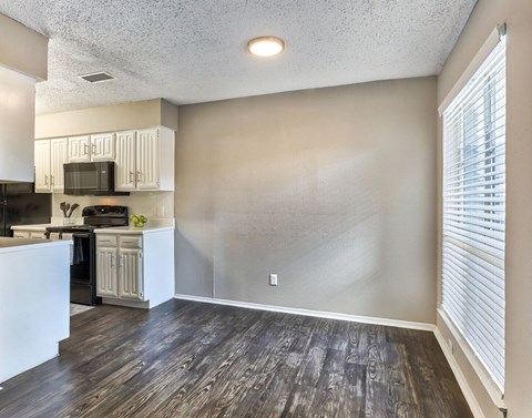 A kitchen with dark wood floors and white cabinets.