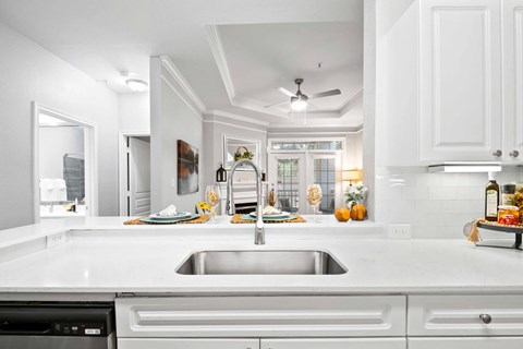 A modern kitchen with a stainless steel sink and white cabinets.