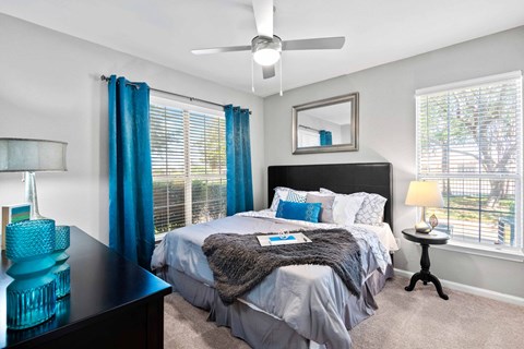 A bedroom with a bed, nightstand, and a ceiling fan.