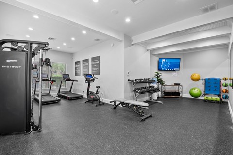 A spacious gym with a variety of equipment including treadmills, elliptical machines, and weight machines.